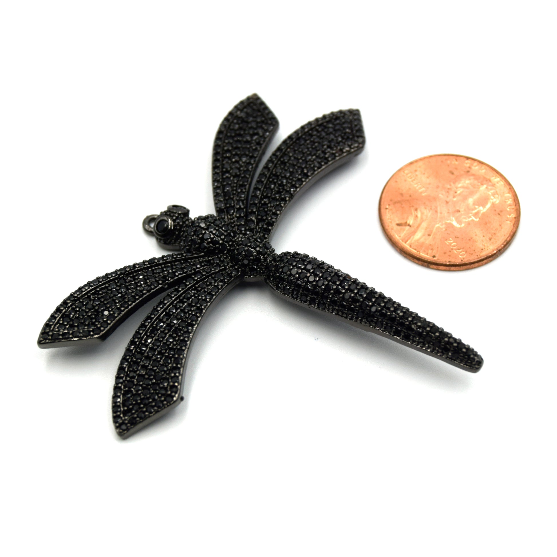  This photo shows a delicate black dragonfly pendant with sparkling black cubic zirconia stones, placed next to a penny for size reference.